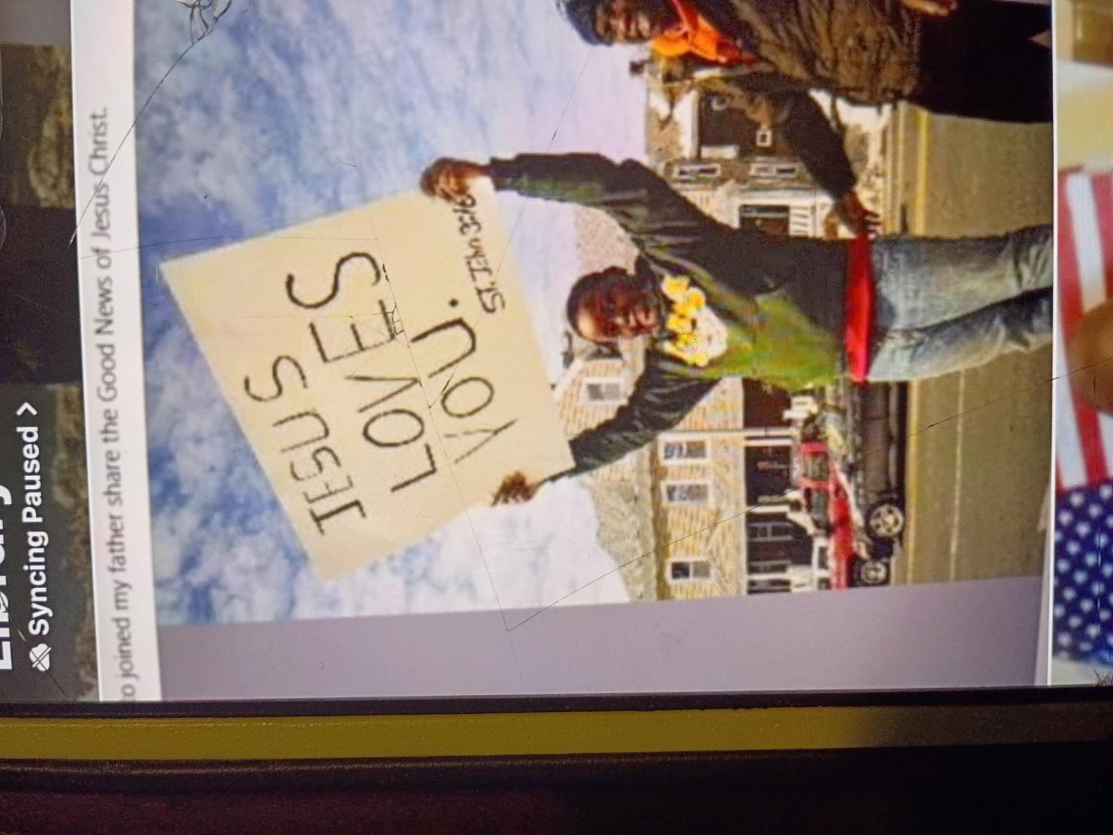 Child holding Jesus Loves You sign during street parade — St. John 3:16